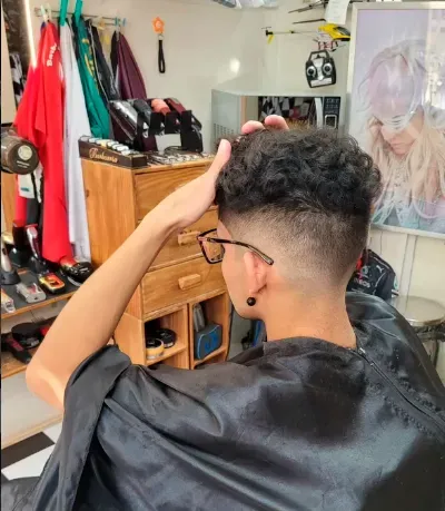 Corte degradê com topo cacheado sendo finalizado por cabeleireiro em São Carlos