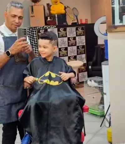 Corte infantil com capa temática do Batman, atendimento kids na barbearia em São Carlos